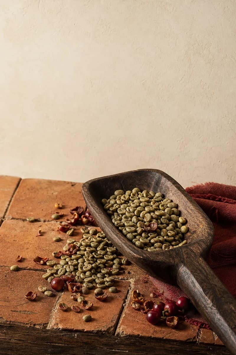 Unroasted Arabica Rio Minas beans in a worn hand-carved wooden coffee scoop