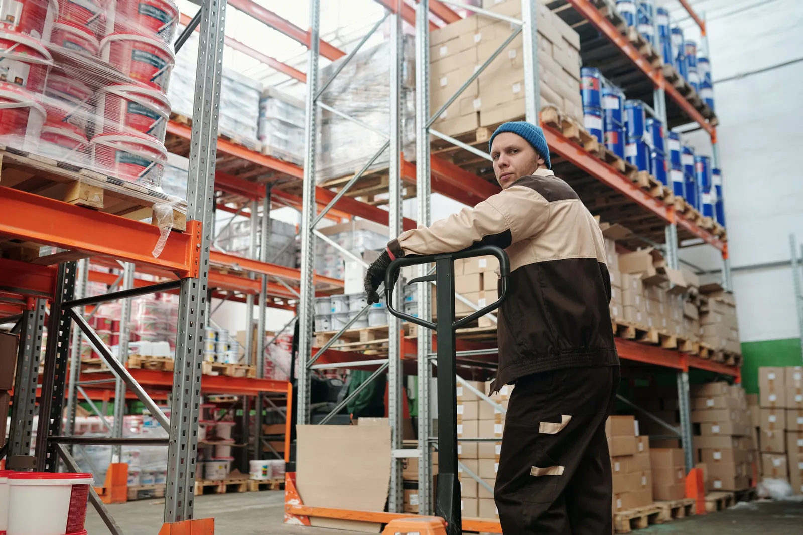 Warehouse worker moving palletised goods in temperature-controlled storage