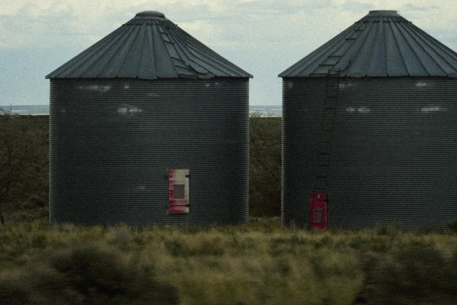 Metal grain storage silos in an open agricultural landscape