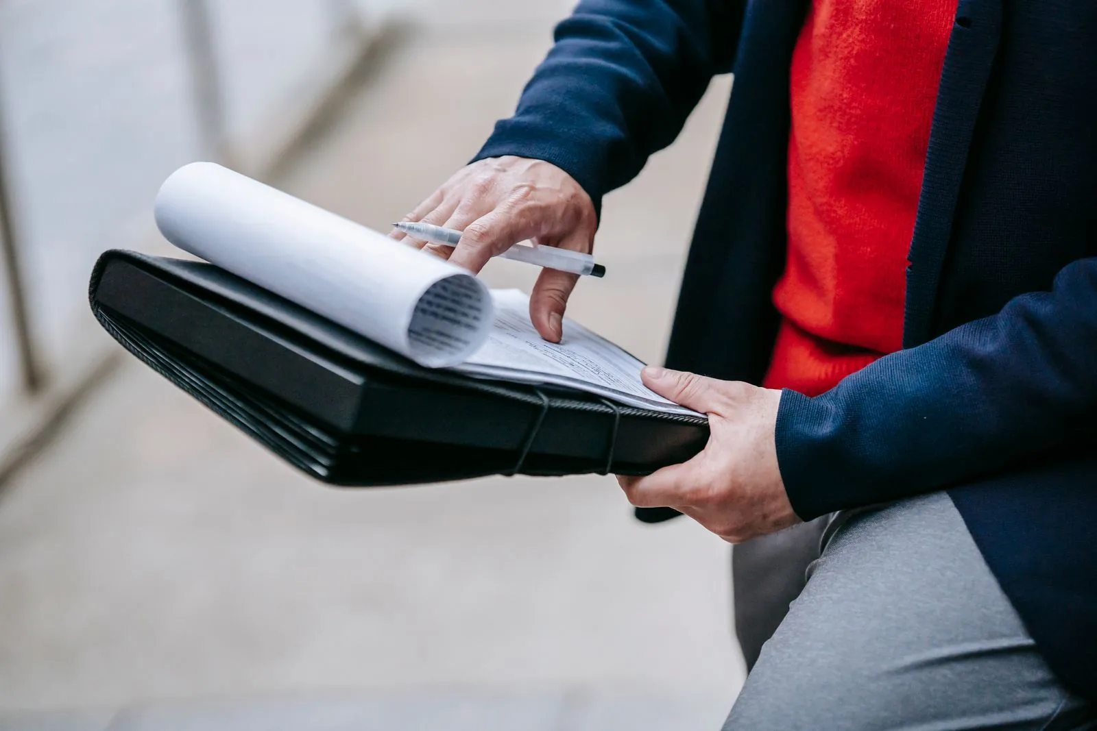 Professional reviewing printed documents in a folder outdoors