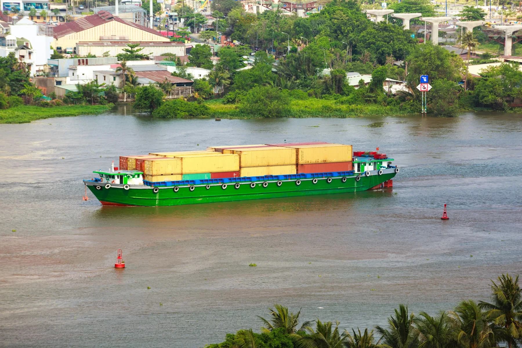 Colourful commercial vessel moving goods along a green waterway