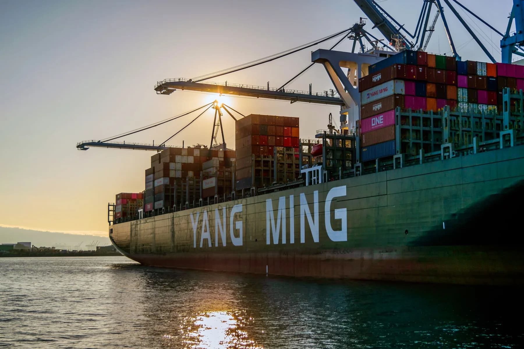 Container ship at a sunlit commercial port