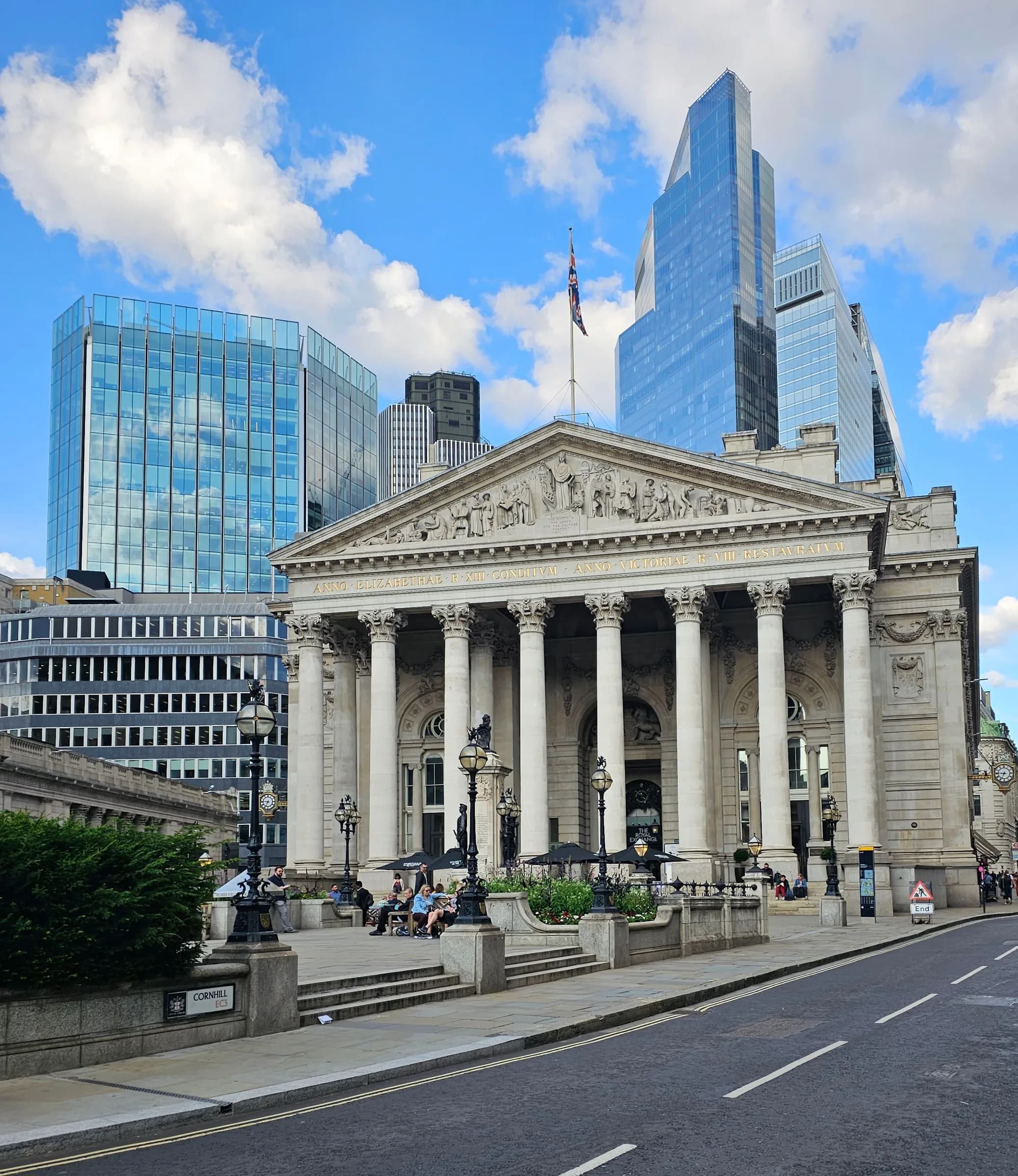 The Royal Exchange in London framed by modern City towers under a blue sky
